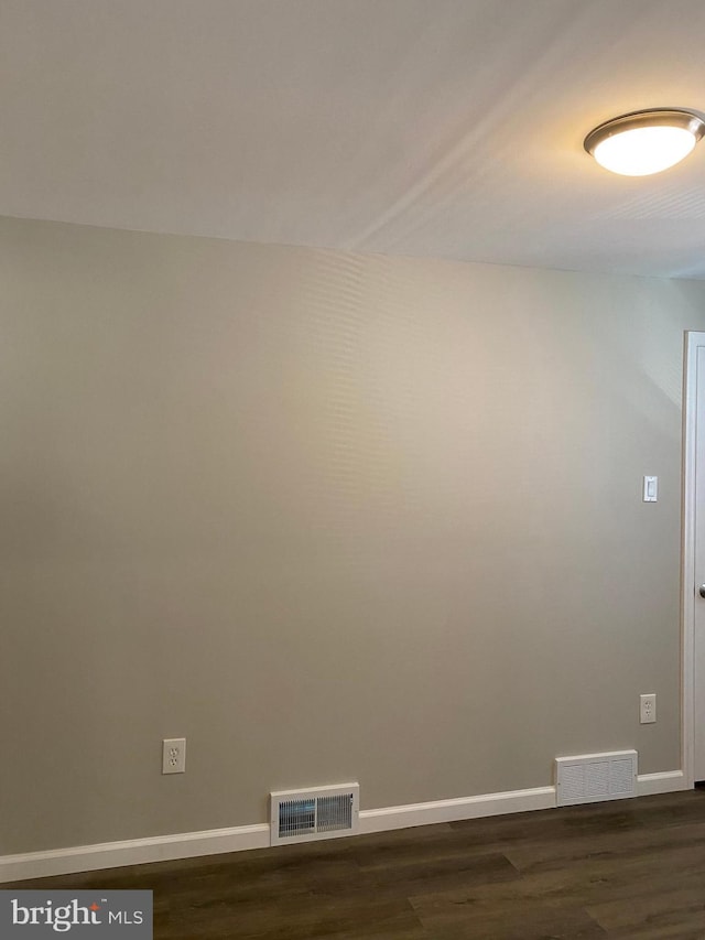 unfurnished room with dark wood-type flooring