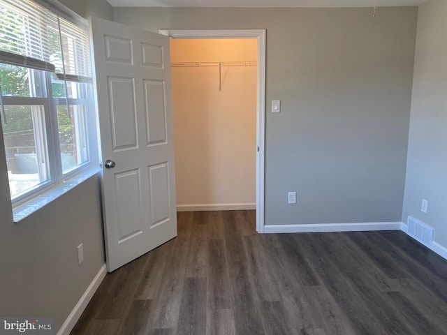 unfurnished bedroom with a walk in closet, dark hardwood / wood-style flooring, and a closet