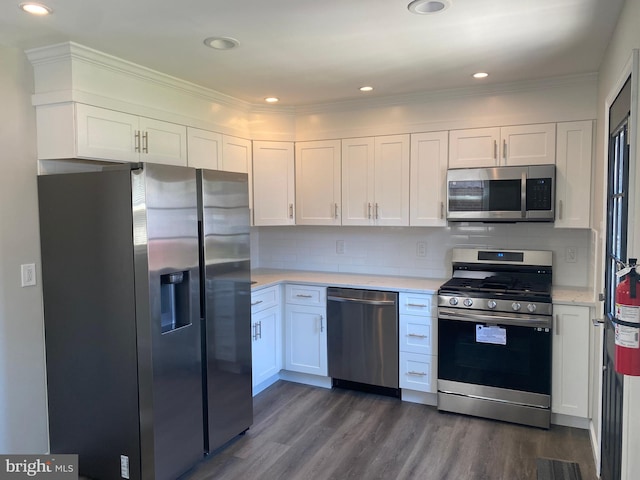 kitchen featuring crown molding, appliances with stainless steel finishes, dark hardwood / wood-style floors, decorative backsplash, and white cabinets