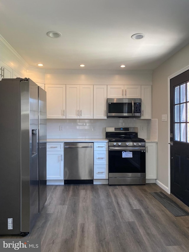 kitchen with decorative backsplash, dark hardwood / wood-style floors, white cabinets, and appliances with stainless steel finishes