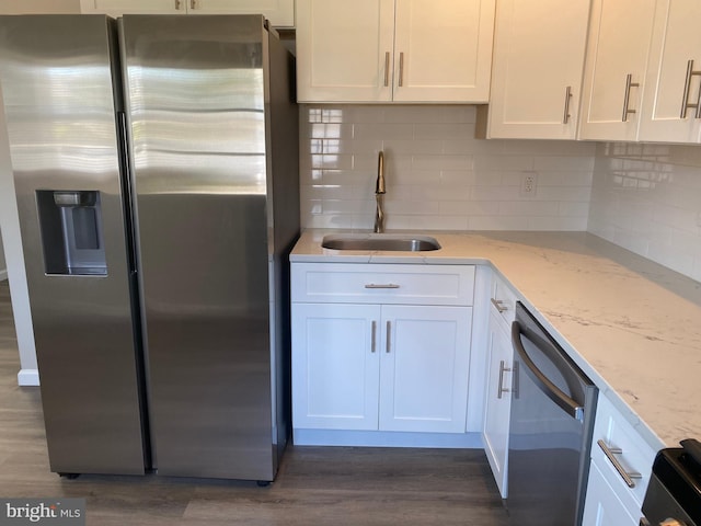 kitchen with appliances with stainless steel finishes, dark hardwood / wood-style floors, sink, white cabinets, and light stone countertops