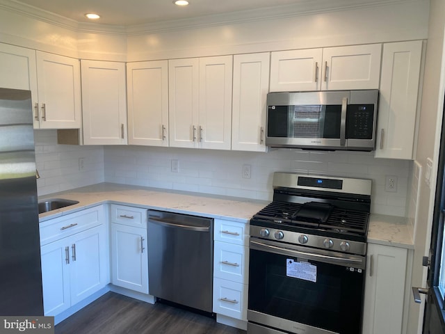 kitchen with white cabinetry, appliances with stainless steel finishes, dark hardwood / wood-style flooring, light stone countertops, and decorative backsplash