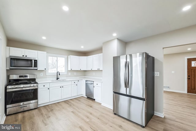 kitchen featuring stainless steel appliances, light hardwood / wood-style floors, sink, and white cabinets