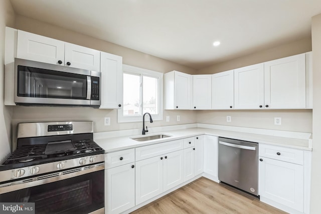 kitchen featuring stainless steel appliances, sink, white cabinets, and light hardwood / wood-style floors