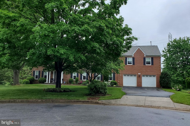 view of front facade with a garage, aphalt driveway, a front lawn, and brick siding