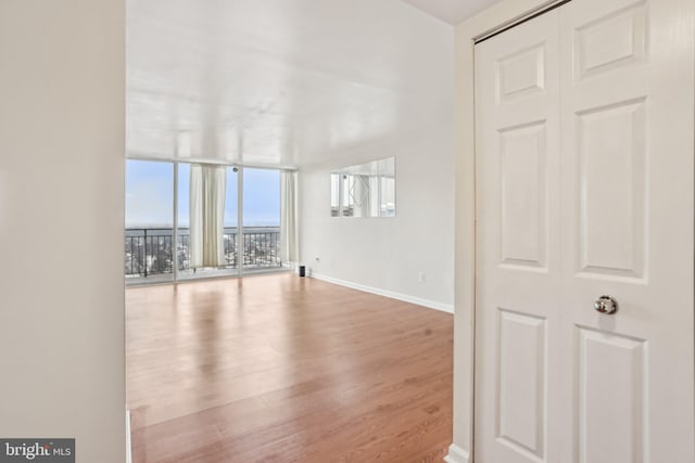 unfurnished room with hardwood / wood-style flooring and a wall of windows