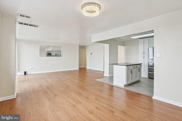 unfurnished living room with an inviting chandelier and light hardwood / wood-style flooring