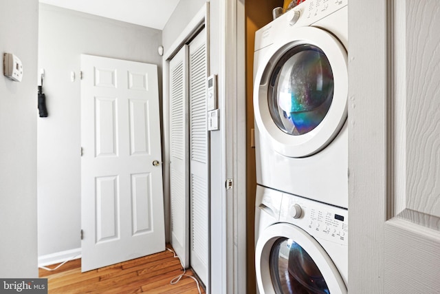 clothes washing area featuring stacked washing maching and dryer and light hardwood / wood-style flooring