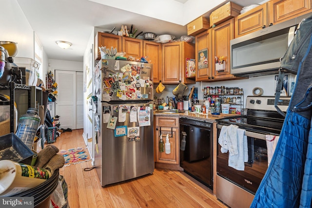 kitchen with sink, light stone countertops, light hardwood / wood-style floors, and appliances with stainless steel finishes