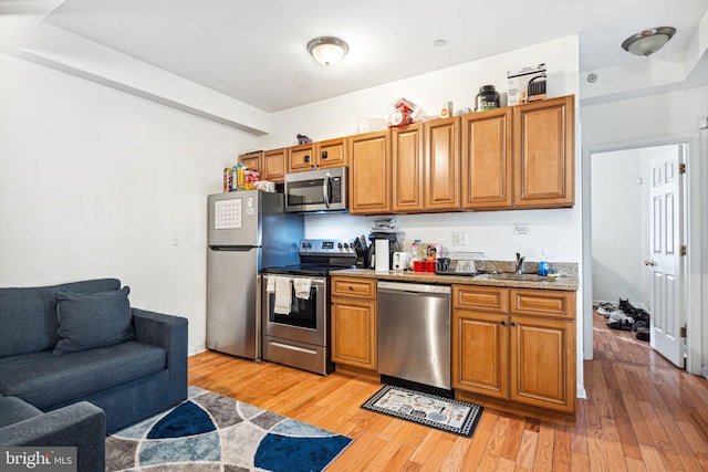 kitchen with stainless steel appliances, sink, and light hardwood / wood-style floors