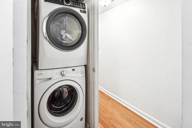 clothes washing area featuring stacked washer / dryer and wood-type flooring