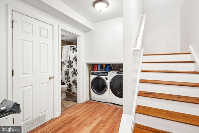 washroom with washing machine and dryer and light hardwood / wood-style floors