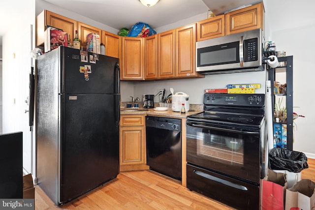 kitchen with light stone countertops, sink, light wood-type flooring, and black appliances