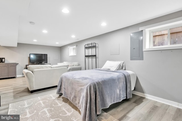 bedroom with multiple windows, light hardwood / wood-style flooring, and electric panel