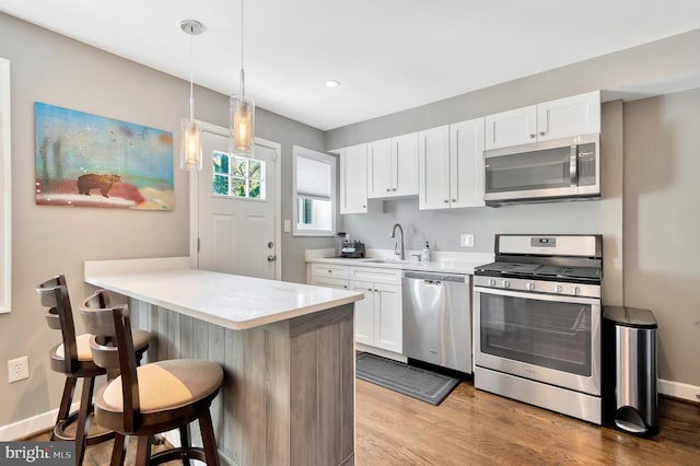 kitchen featuring white cabinetry, pendant lighting, a kitchen breakfast bar, and appliances with stainless steel finishes