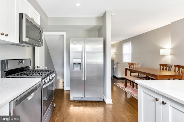 kitchen with light stone counters, appliances with stainless steel finishes, dark hardwood / wood-style floors, and white cabinets