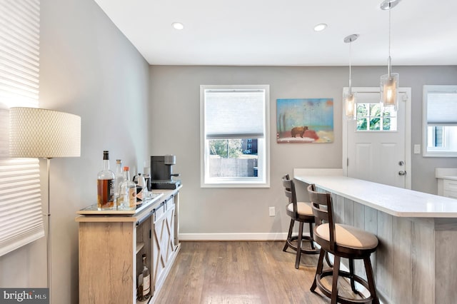 kitchen with hanging light fixtures, hardwood / wood-style floors, kitchen peninsula, and a breakfast bar