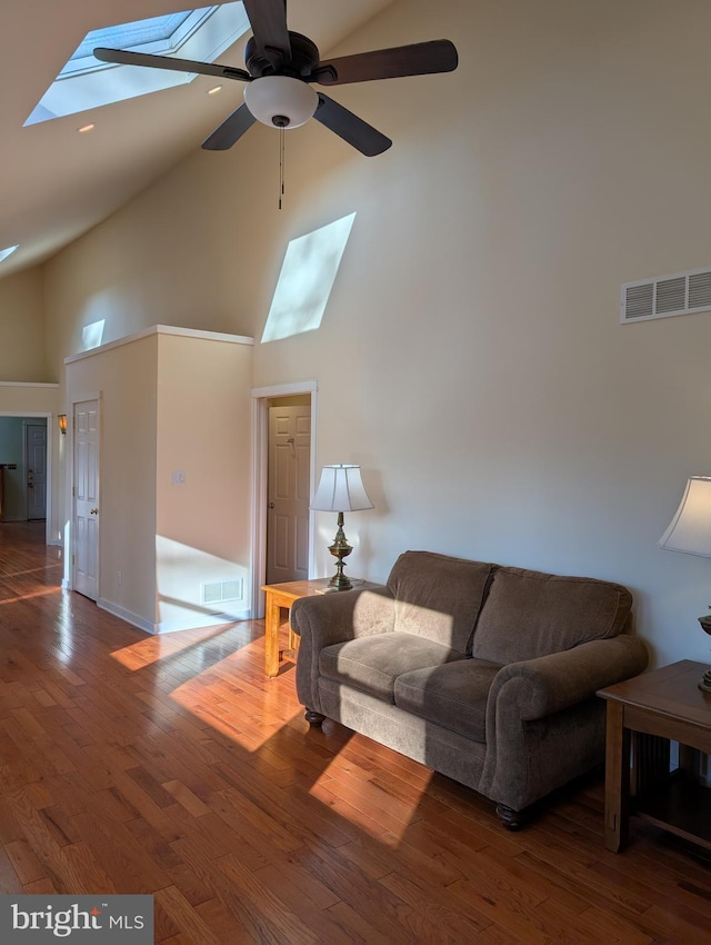 living room featuring a skylight, high vaulted ceiling, dark hardwood / wood-style floors, and ceiling fan