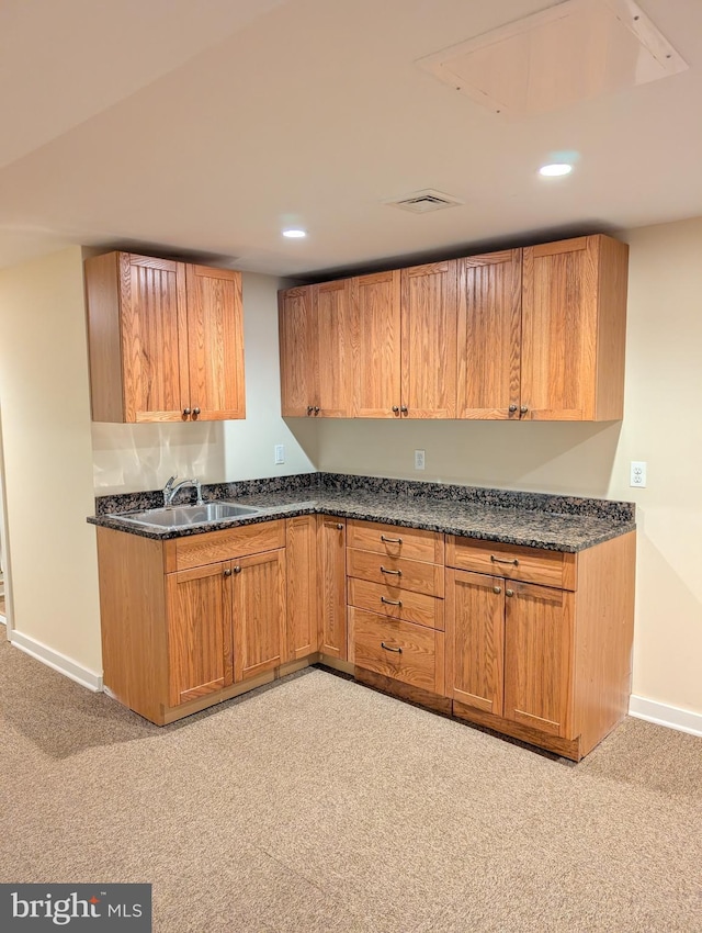 kitchen featuring dark stone countertops, sink, and light colored carpet