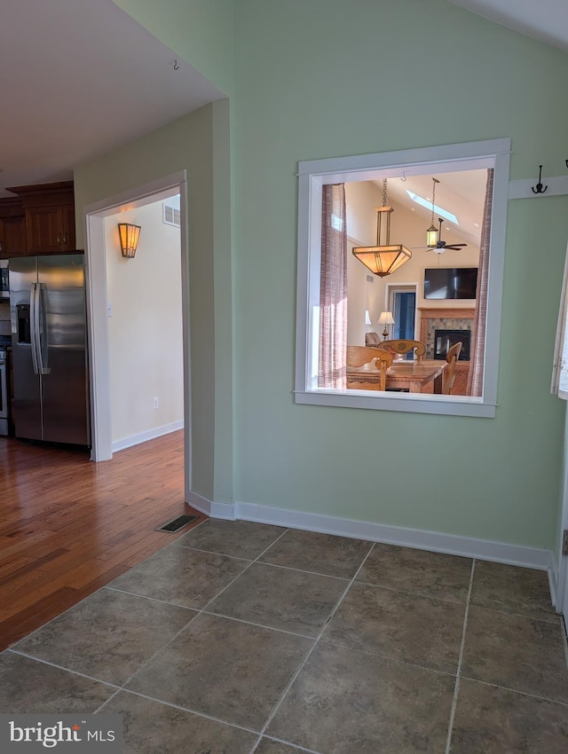 unfurnished dining area with vaulted ceiling and dark tile patterned floors