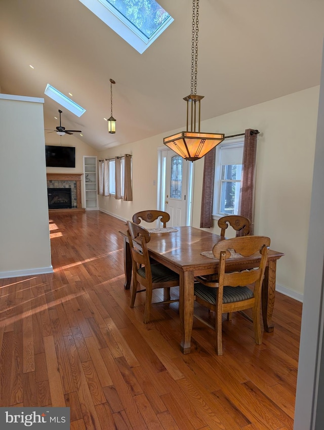 dining area with ceiling fan, lofted ceiling with skylight, and hardwood / wood-style floors