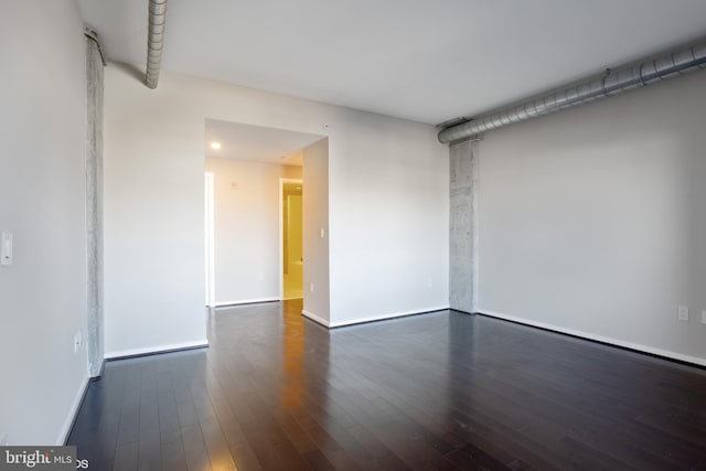 spare room with baseboards and dark wood finished floors