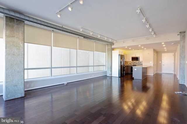 unfurnished living room featuring rail lighting and dark wood-style floors