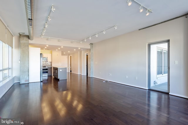 unfurnished living room with dark wood-style floors, baseboards, and track lighting