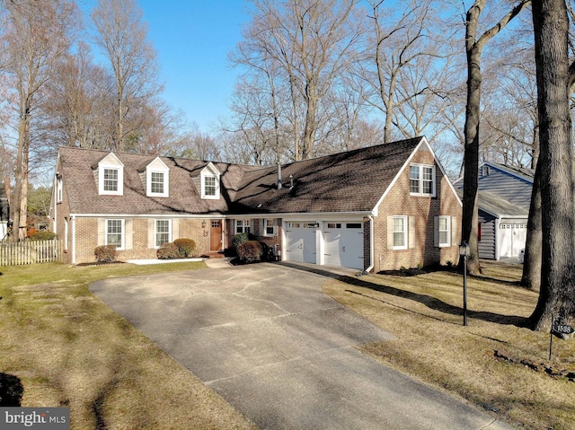 cape cod house with a front yard, fence, driveway, a garage, and brick siding