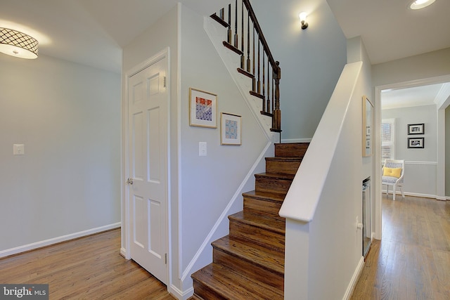 staircase featuring wood finished floors and baseboards