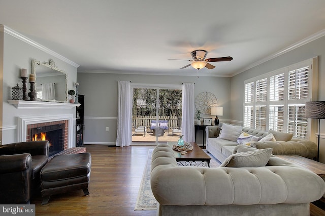 living room with ornamental molding, a ceiling fan, dark wood finished floors, baseboards, and a brick fireplace