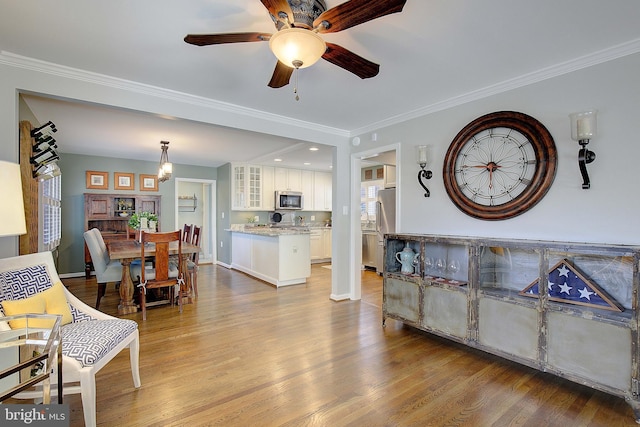 interior space featuring a ceiling fan, wood finished floors, baseboards, and ornamental molding