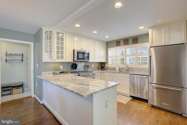 kitchen with white cabinets, appliances with stainless steel finishes, glass insert cabinets, and a sink