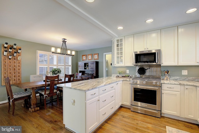 kitchen featuring white cabinetry, a peninsula, light wood-style flooring, and appliances with stainless steel finishes