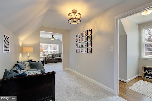 interior space featuring light colored carpet, lofted ceiling, visible vents, and baseboards