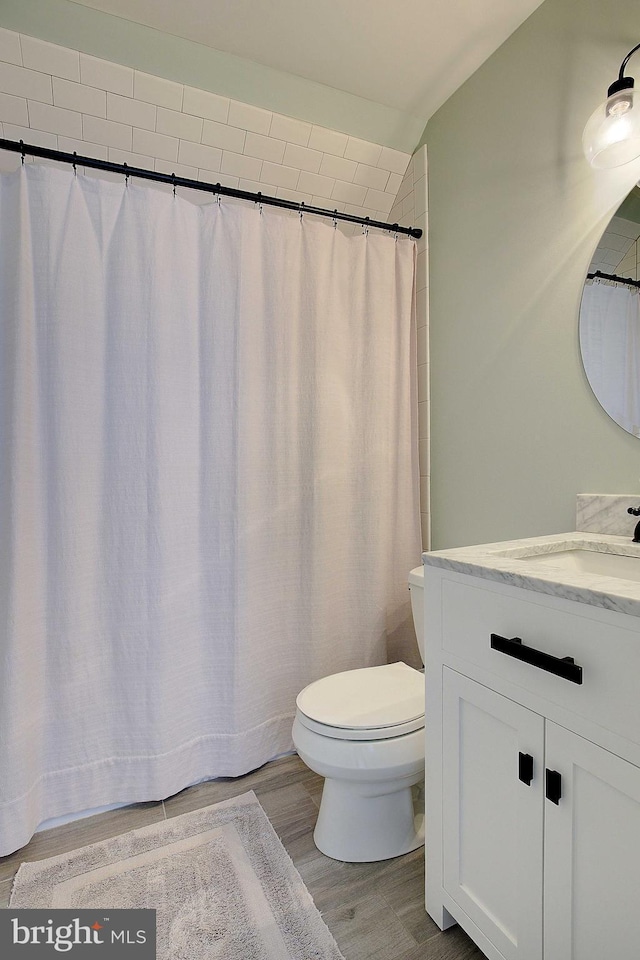 bathroom with vaulted ceiling, toilet, vanity, and wood finished floors