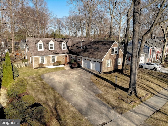 cape cod house featuring an attached garage, fence, brick siding, and driveway