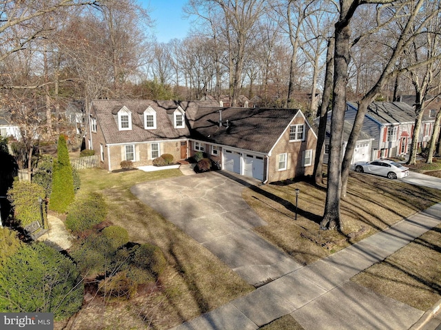 view of front of property featuring fence, driveway, an attached garage, brick siding, and a residential view