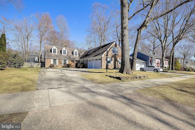 cape cod-style house with brick siding, driveway, a front yard, and fence