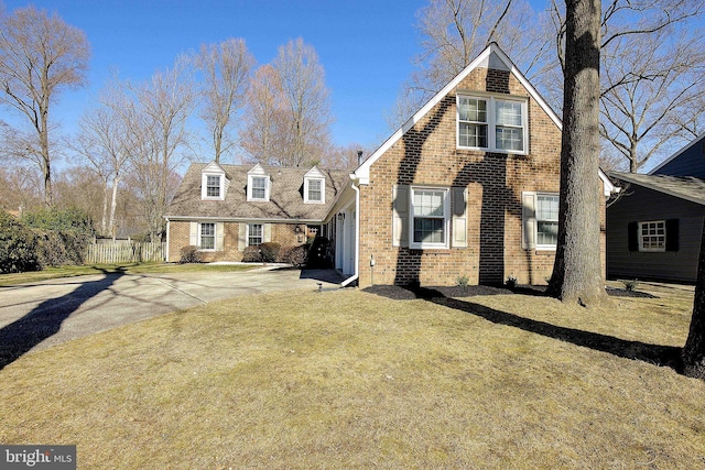 view of front of house featuring fence, brick siding, and driveway