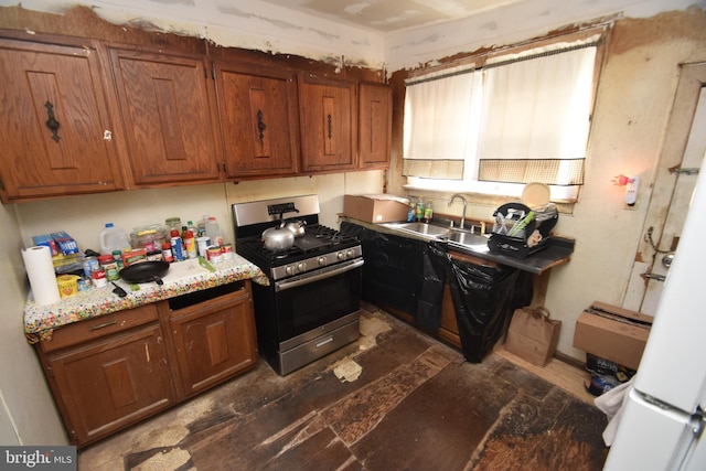 kitchen with light countertops, brown cabinets, a sink, and stainless steel gas range oven