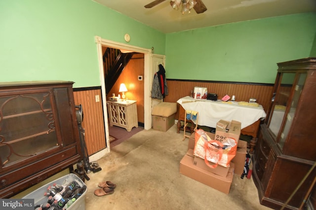 bedroom with wood walls, ceiling fan, and wainscoting