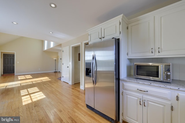 kitchen featuring appliances with stainless steel finishes, light hardwood / wood-style flooring, white cabinetry, and light stone counters