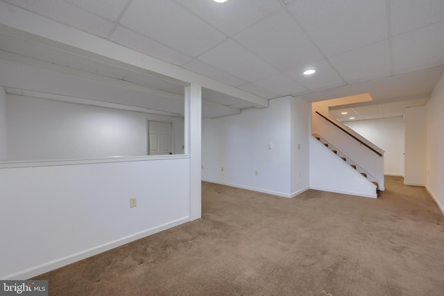 basement with light colored carpet and a drop ceiling