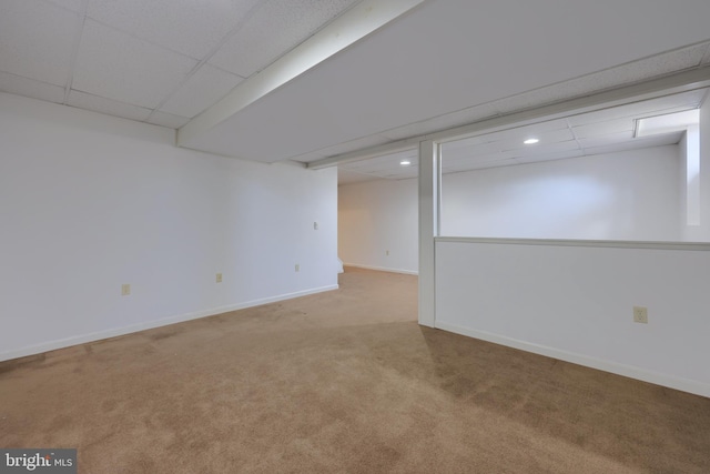 basement with a drop ceiling and light colored carpet