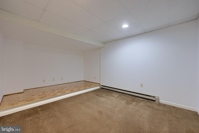 carpeted spare room with a paneled ceiling and a baseboard radiator