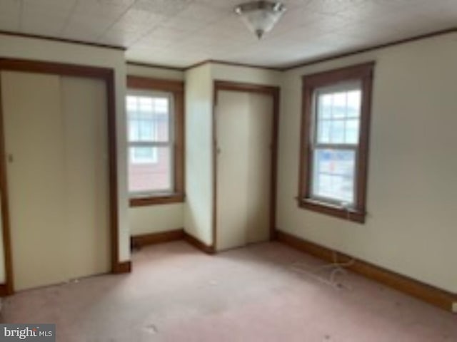 unfurnished bedroom featuring multiple closets and light colored carpet