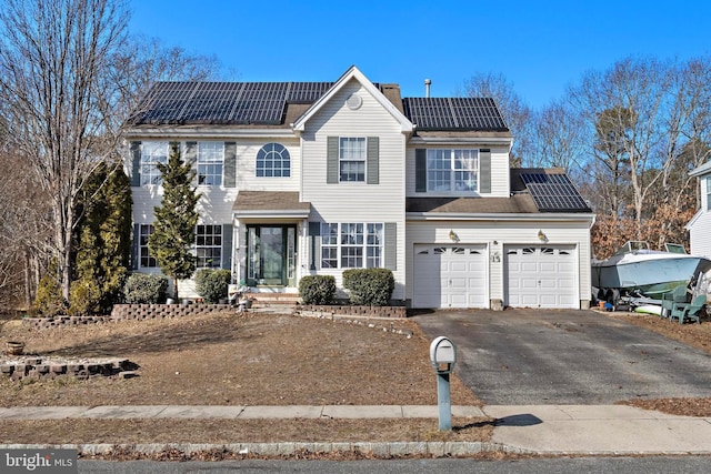 view of front of property featuring a garage and solar panels