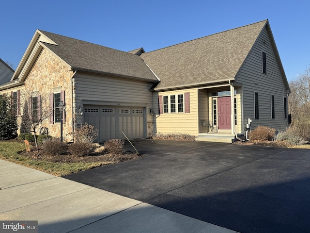 view of front facade with aphalt driveway, stone siding, roof with shingles, and an attached garage