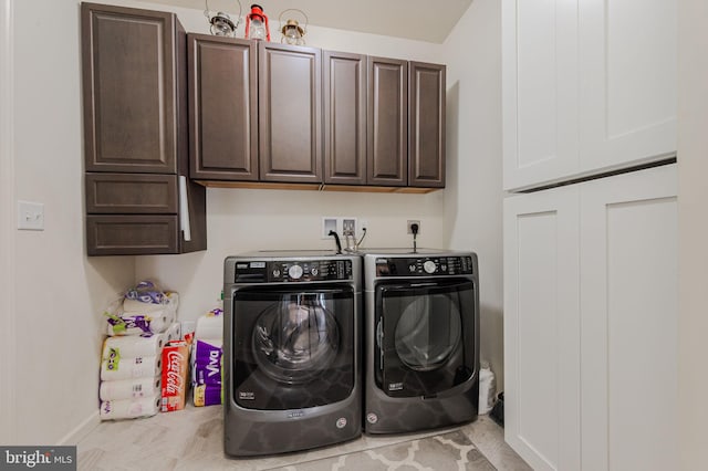 washroom featuring washer and clothes dryer, cabinet space, and baseboards